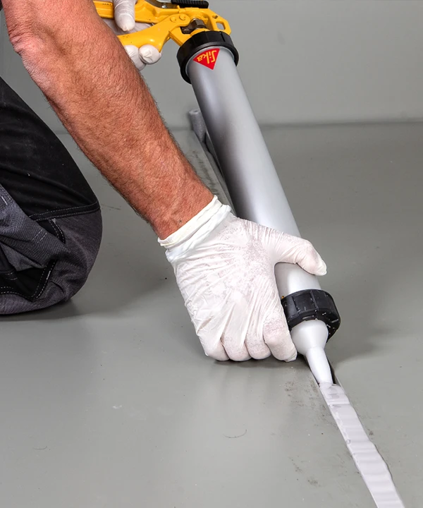 Workers filling floor joints with sealant series products